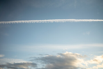 Evening sky with clouds with white stripes from the plane.