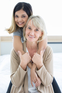 Happy mix skin family living together, adopted caucasian mother and Asian daughter cuddle each other with smiles. Idea for love and sharing time of stepmother, stepdaughter, mother or daughter in law