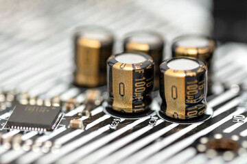A macro shot of five capacitors in a metal housing, soldered to the motherboard of a desktop...