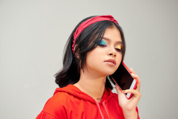 Naklejka premium Photo of young happy lady standing isolated over gray background talking by mobile phone