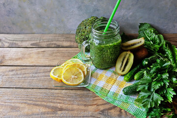 Green home-made smoothies in a glass jar on a wooden table on a checkered napkin. ingredients-lemon, spinach, kiwi, broccoli. Copy space. Horizontal.