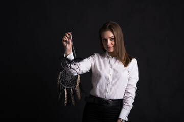 Young girl holding dreamcatcher in her arms in studio on black background