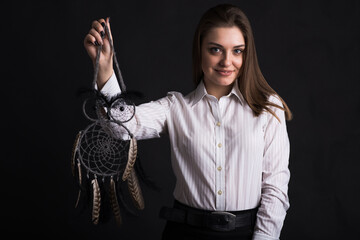 Young girl holding dreamcatcher in her arms in studio on black background