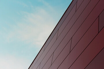 wall of red panels, modern building, exterior against blue sky, diagonal view