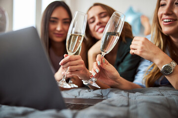 Close female friends lying on the bed with champagne flutes