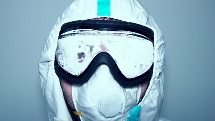 Face of hospital healthcare worker adjusting goggles and face mask in protective gown