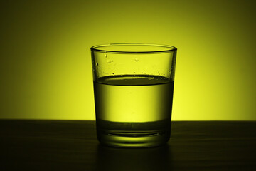 A glass with water at yellow background