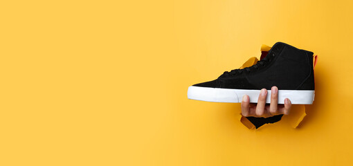 The man's right hand went through the yellow paper wall while holding a black shoe. Suitable as a...