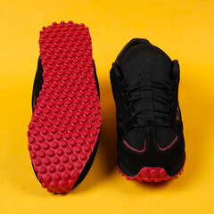 Black sneakers isolated on a yellow background, seasonal shoes for walking and sports, a pair of stylish sneakers on a colored background. Concept photo of sneakers. Sport shoes. Trendy shoe fashion