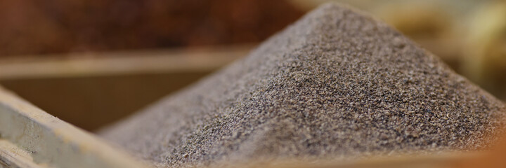 Selling spices in specialized store. Slide of black ground pepper close up.