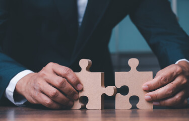 Businessman hand connecting jigsaw puzzle on desk, Business solutions, concept of success and...