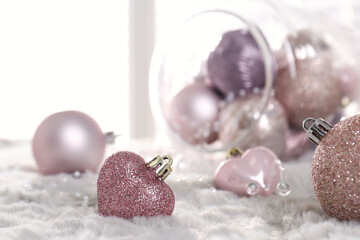 Fototapeta na wymiar Beautiful pink Christmas baubles on white fur. Space for text