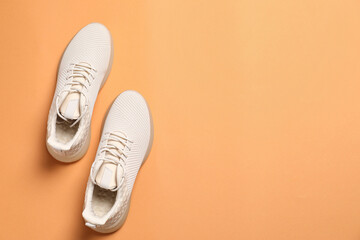Pair of stylish sport shoes on orange background, flat lay. Space for text