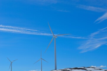 windmill farm on snowy mountain in northern Norway in bright sunshine and blue sky backdrop