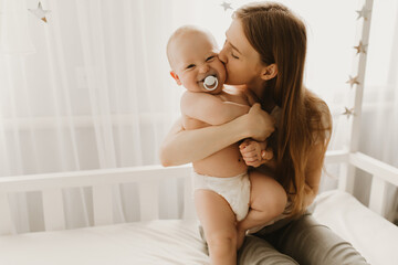 Happy family, child and parenting concept, young mom hugs her little child - obrazy, fototapety, plakaty