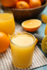 Freshly made juice, oranges and reamer on blue table