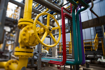Fototapeta na wymiar Oil refinery plant. Close-up of yellow gas valve and high-pressure tubes. Color pipes and grey pipelines on background. Small depth-of-field