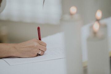 Closeup of the bride signing the marriage certificate on the wedding day