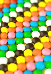 Rainbow bright candies on yellow background. Cheerful colorful creative wallpaper