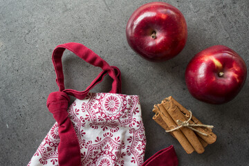 Kitchen apron, red apples, flour, cinnamon sticks top view photo. Making an apple pie. Domestic...