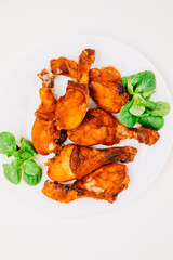 fried chicken thigh. copy space. chicken drumstick with green leaves on a white table 