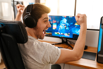 Excited guy making winner gesture while playing video game on computer