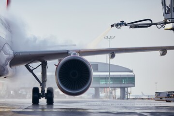 Deicing of aircraft wing before flight. Winter frosty day at airport. 