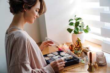 Happy brunette girl examining minerals and stones set at home shrine