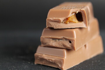Day chocolate bar pieces of chocolate lie on top of each other with a stack of macro close-ups on a black background