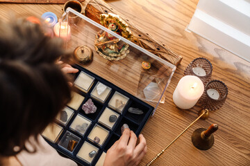Brunette girl examining minerals and stones set at home shrine