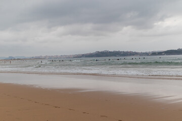 Fototapeta na wymiar Surfing afternoon in a cloudy day with friends, Cantabria, Spain