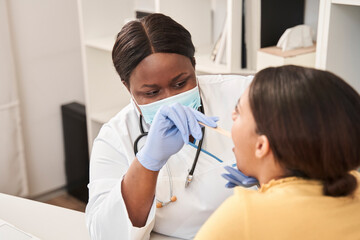 Obraz premium Doctor examining a woman and looking in her throat