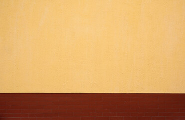 yellow wall with plaster and brown tiles below, exterior