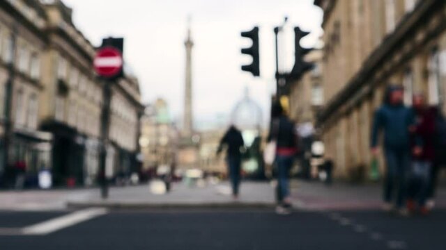 Abstract blurred people crossing a road at a designated pedestrian crossing with traffic lights