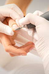 Closeup of manicure master removes nail polish uses an electric nail file in a nail salon - obrazy, fototapety, plakaty