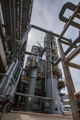 Distillation tower (column) on blue sky with sun background. Oil refinery plant in a desert. Wide-angle view