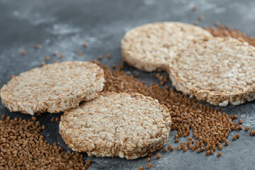 Puffed crispbread and raw buckwheat on marble surface