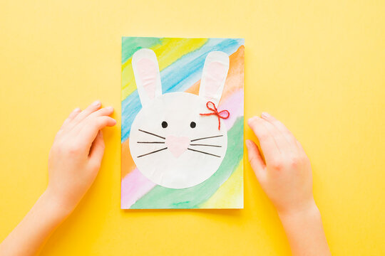 DIY Easter card. How to make paper bunny for Easter greetings. Step by step photo instruction. Kids hands hold Finished card. Step 7.