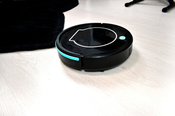 Robot vacuum cleaning on laminate wood floor and carpet. Modern digital technology. Innovation artificial intelligence housekeeping. Lifestyle concept. Smart house.