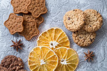 Crispy, aromatic, chocolate and caramel cookies, dried orange slices, anise stars. Stock photo of festive and sweet pastries in close-up.