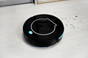Close up robot vacuum cleaning on laminate wood floor. Modern digital technology. Innovation artificial intelligence housekeeping. Lifestyle concept. Smart house.