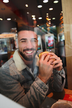 hombre feliz comiendo hamburguesa. Concepto de comida rápida. Felicidad. Salud. Espacio para texto