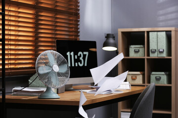 Modern electric fan and flying paper in office