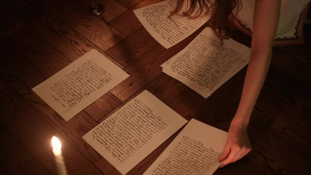 writer woman in night shirt is writing poem in a dark room with a candle light