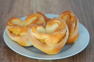Hefegebäck mit Zuckerstreuseln in Nahaufnahme. Selbst gebackene Brötchen in Herzform aus Hefeteig.