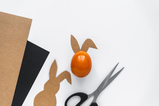 Ein Osterei mit Papier Hasenorhen, eine Schere und Bastel Karton auf einem wei&szlig;en Hintergrund. Kreativit&auml;t, Idee, Ostern.