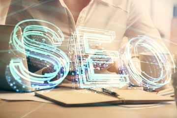 Double exposure of SEO sketch hologram and woman holding and using a mobile device.