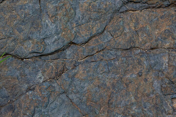 The surface of an old rock with cracks and moss. Old rock texture (wild background)
