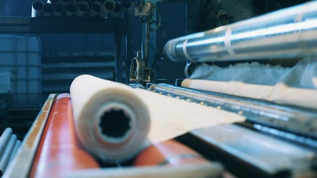 Paper roll making machine operated by a factory worker