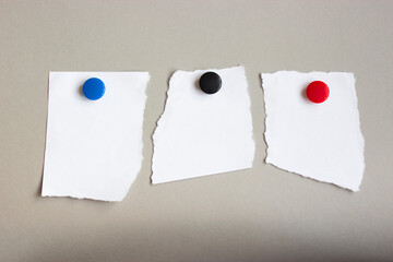 three pieces of white paper hanging on the wall on colorful magnets